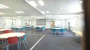 Large seminar room with chairs arranged around 6 or 7 round tables.